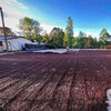 coffee farmer raking coffee beans as they dry on a large patio