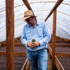Coffee farmer walking through rows of coffee beans drying on raised beds