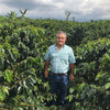 Farmer standing the middle of a coffee farm.